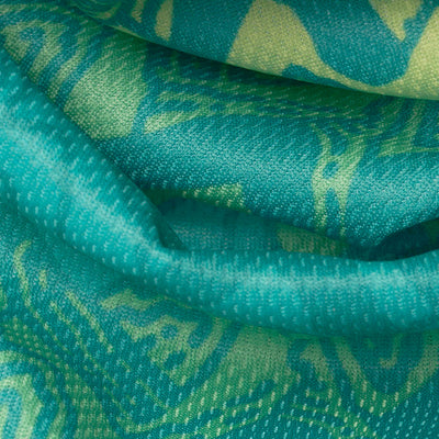 Close-up of turquoise and green fabric with a textured, patterned design. The fabric appears to be soft and folds naturally, showcasing its vibrant colors and intricate woven details. Part of the Wilderdog x Stio Bandana series, this cooling bandana is perfect for active pups.