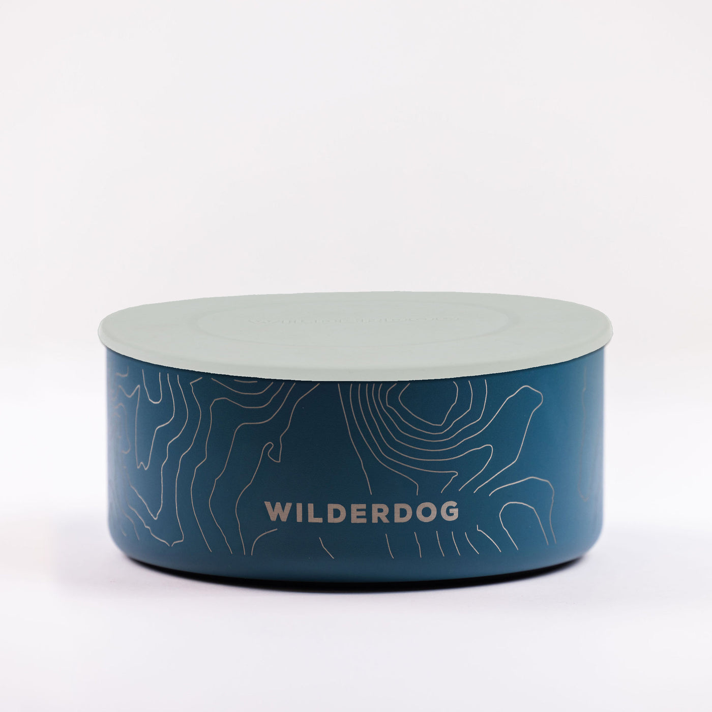 The Stainless Steel Dog Bowl is round and blue, featuring a topographic map design with "WILDERDOG" written on the side in white text. It comes with a flat, light-gray lid, is BPA-free, and set against a plain white background.