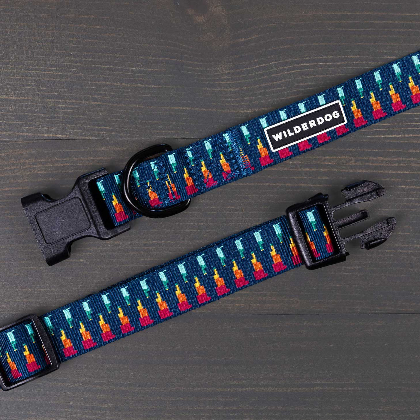 A dog collar from the Ultralight Collection, labeled "Marina Ultralight Collar," is laid flat. It features a black plastic buckle, adjustable strap, and durable nylon webbing. The collar's design showcases a vibrant pattern of red, yellow, and blue hues reminiscent of a mountain landscape against a dark background.