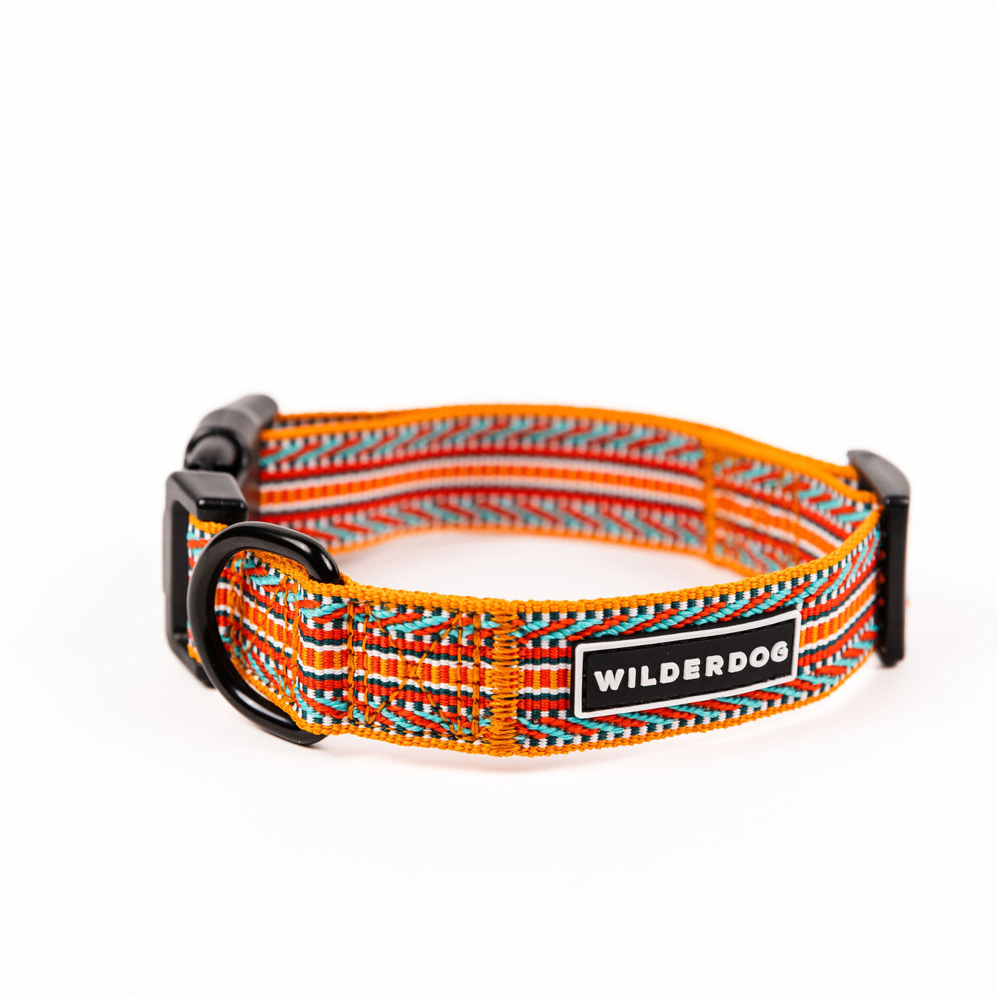 The Sienna Ultralight Collar showcases a vibrant woven pattern with red, orange, blue, and black stripes. Equipped with a heavy-duty plastic clip and a sturdy metal D-ring for leash attachment, it is crafted from ultralight nylon webbing to ensure both durability and comfort. A tag branded "WILDERDOG" is prominently displayed on the exterior. The background is white.