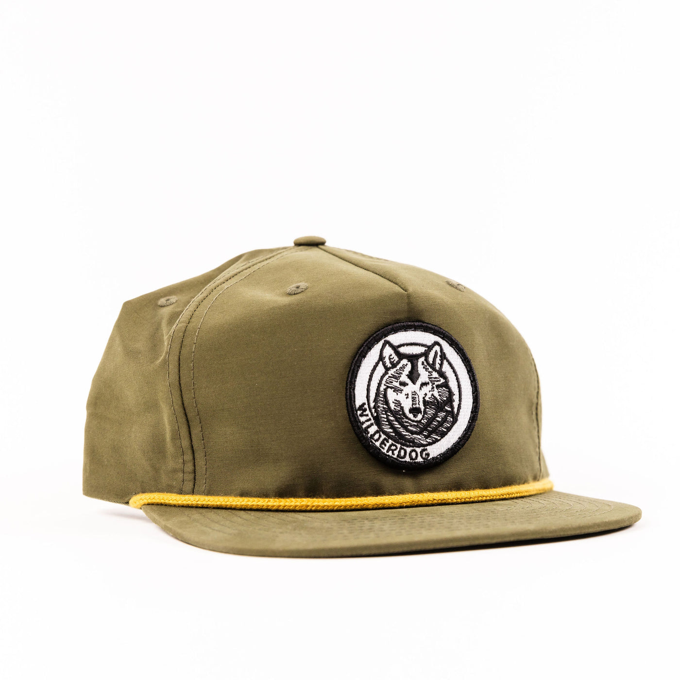 The Wilderdog Gramps Hat is an olive green baseball cap with a flat brim and a circular embroidered patch on the front, featuring a stylized wolf head with the text "WILDERDOG" around it. Echoing classic golf vibes, this hat also includes a yellow rope detail across the base of the brim.