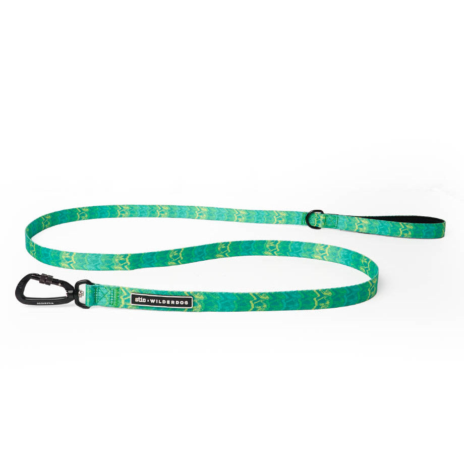 The Wilderdog x Stio Ultralight Leash is a vibrant green dog leash with a wavy pattern, inspired by Teton designs. It features a black carabiner clip on one end and a handle loop on the other, along with an adjustable buckle positioned near the handle loop. The leash also includes a branded tag labeled "Wilderdog.