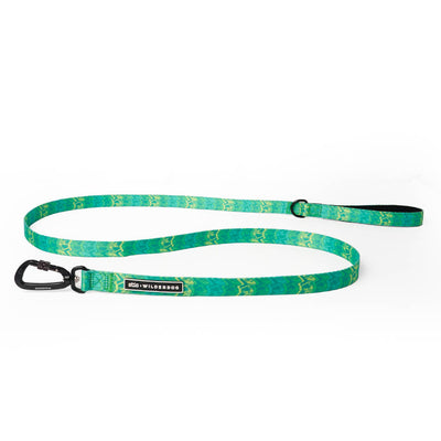 The Wilderdog x Stio Ultralight Leash is a vibrant green dog leash with a wavy pattern, inspired by Teton designs. It features a black carabiner clip on one end and a handle loop on the other, along with an adjustable buckle positioned near the handle loop. The leash also includes a branded tag labeled "Wilderdog.