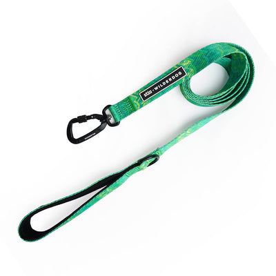 The Wilderdog x Stio Ultralight Leash is a durable dog leash featuring Teton-inspired designs in green and blue. It includes a black clasp and handle, with a small black tag that reads "WILD ONE" stitched near the clasp. The ultralight leash is coiled neatly in the image.