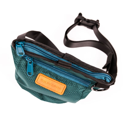 A stylish Dog Training Treat Pouch featuring a teal rectangular design with a black adjustable waist strap and buckle. It boasts two blue zippers on top and a brown patch with text. The diamond-patterned fabric adds to its chic appearance, while the slightly open position reveals its spacious inner compartment, perfect for holding treats during training sessions.